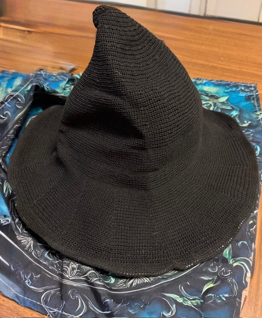 Black woven witch hat photographed on a decorative altar cloth