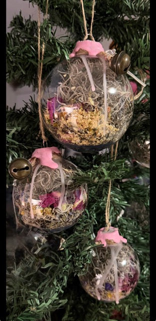 Three handmade Self-Love & Harmony Witch Balls hanging among greenery