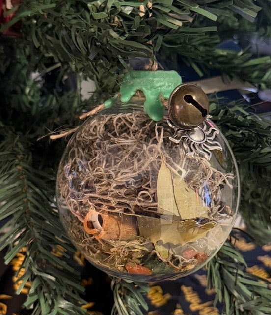 Abundance and Prosperity Witch Ball hanging among evergreen branches, with natural filling and green wax